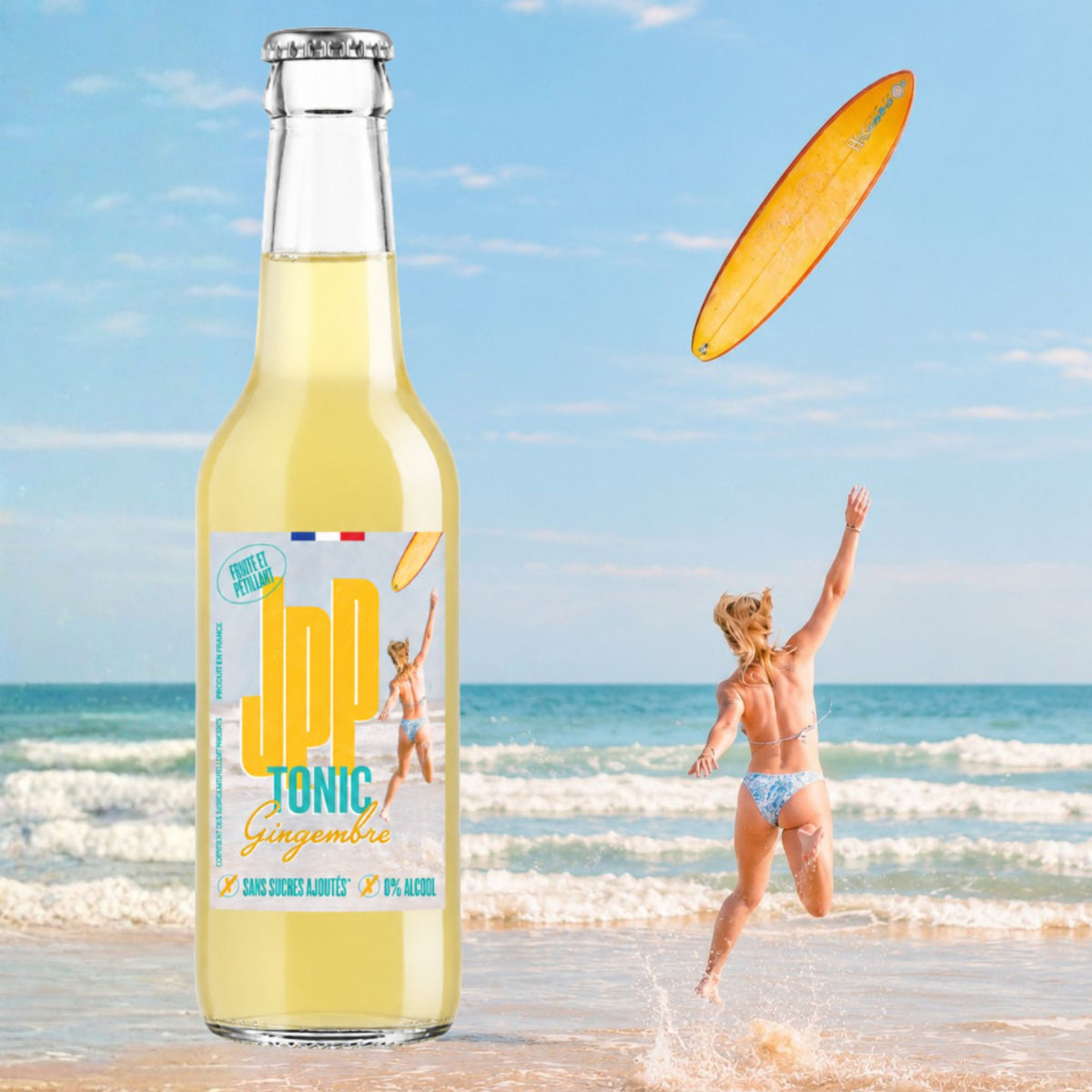 Bouteille de JPP Tonic Gingembre sur une plage, une femme lance sa planche de surf