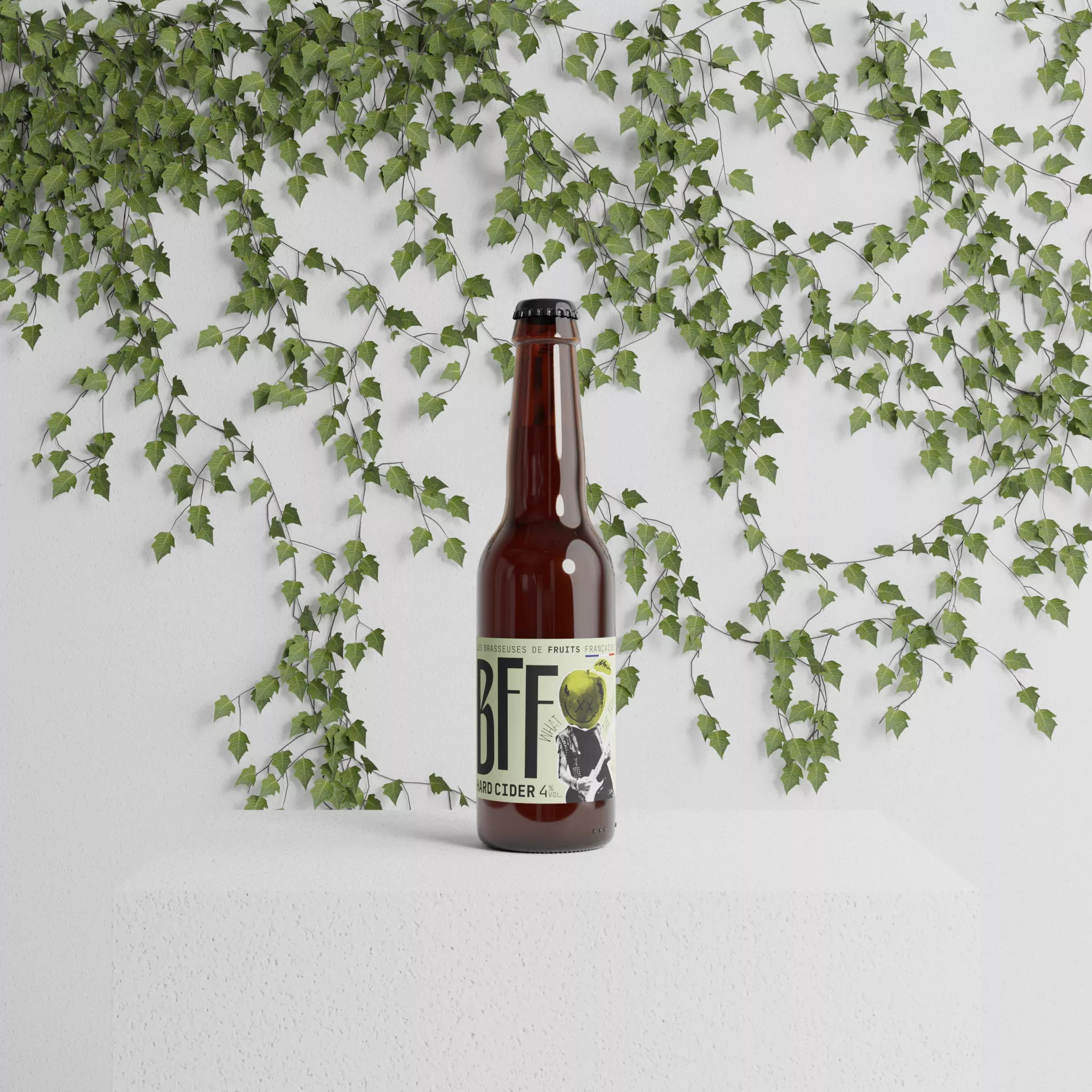 "Bouteille de BFF pomme posée sur un socle blanc, entourée de feuilles grimpantes sur fond mural — une mise en scène épurée et végétale qui reflète l’origine naturelle et vivante du fruit dans chaque bouteille.